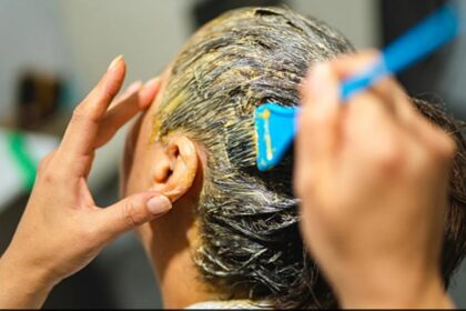 किचन की चीजों से बनी नेचुरल हेयर डाई लगाती हुई महिला, बालों में ऑलिव ऑयल और कॉफी मिश्रण लगाते हुए