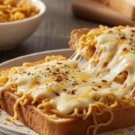 चीज़ और चिली फ्लेक्स के साथ मैगी नूडल्स को टोस्टेड ब्रेड स्लाइस पर फैलाया गया है। बैकग्राउंड में मैगी का पैकेट, एक कटोरी मैगी और कुछ ब्रेड स्लाइस रखे हैं।