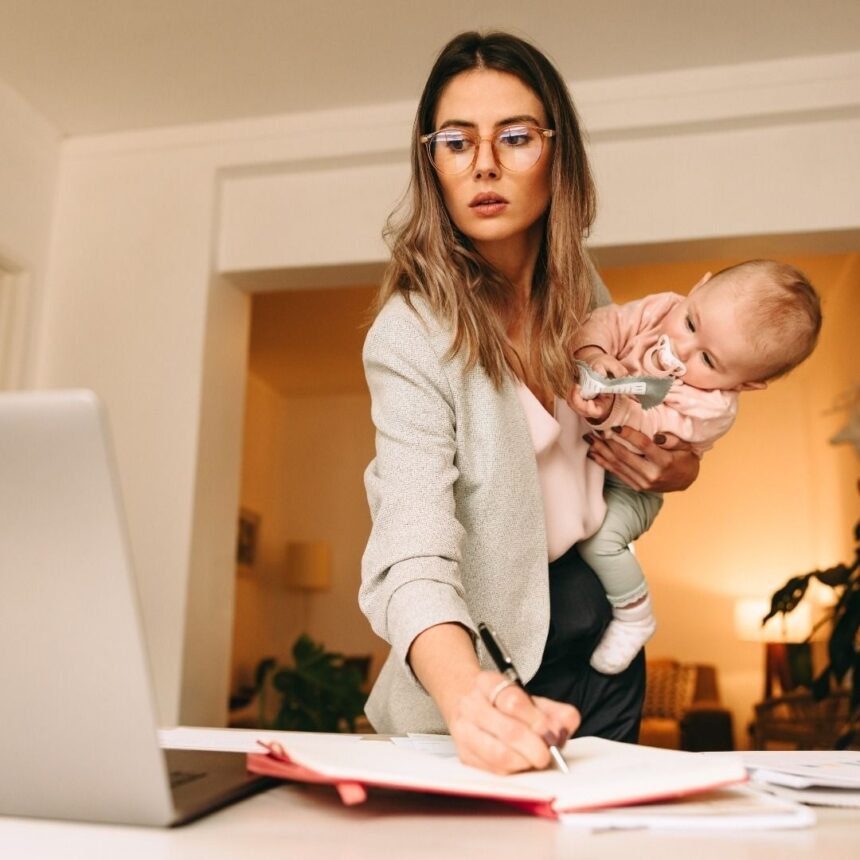 मातृत्व के बाद करियर में वापसी करती हुई एक भारतीय महिला, लैपटॉप पर काम करती हुई और बच्चे की देखभाल के बीच संतुलन बनाते हुए।
