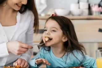 “माता-पिता अपने बच्चे को सब्ज़ियाँ और फल खिलाते हुए, हेल्दी और मजेदार तरीके से।