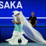 ऑस्ट्रेलियन ओपन के कोर्ट पर टेनिस खेलती नाओमी ओसाका, सफ़ेद “जेलीफ़िश ड्रेस” में, जो मातृत्व और भावनात्मक अभिव्यक्ति से प्रेरित एक अनोखा स्पोर्ट्स फैशन लुक दर्शाती है।