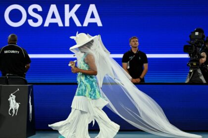 ऑस्ट्रेलियन ओपन के कोर्ट पर टेनिस खेलती नाओमी ओसाका, सफ़ेद “जेलीफ़िश ड्रेस” में, जो मातृत्व और भावनात्मक अभिव्यक्ति से प्रेरित एक अनोखा स्पोर्ट्स फैशन लुक दर्शाती है।