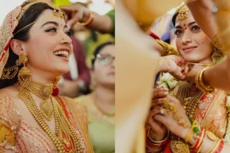 पारंपरिक भारतीय दुल्हन लाल और सुनहरे लहंगे में, भारी गोल्ड ज्वेलरी पहने हुए, शादी की रस्म के दौरान मुस्कुराती हुई