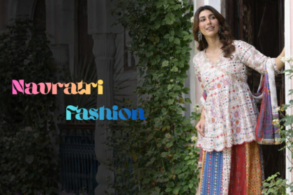 एक खूबसूरत साउथ एशियन महिला पारंपरिक घर के दरवाजे पर खड़ी है, चारों तरफ हरियाली और फूल हैं। उसने मल्टीकलर प्रिंटेड कुर्ता, स्कर्ट और दुपट्टा पहना हुआ है। बाईं ओर “Navratri Fashion” लिखा हुआ है।