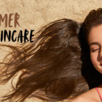 A woman lying on sand with glowing skin, applying sunscreen on her face, representing summer skincare and sun protection. The image highlights healthy, radiant skin during summer with the text “Summer Skincare” displayed.