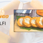 कटे हुए आम के स्लाइस में भरी हुई क्रीमी मैंगो कुल्फी, लकड़ी के बोर्ड पर सुंदर तरीके से सजाई हुई