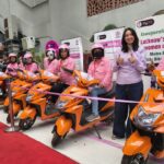 Women riders with orange EV scooters during the launch of Lucknow Metro's MyDidi Women-Only EV Bike Shuttle Service, promoting safe last-mile connectivity and women empowerment in Lucknow.