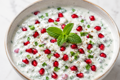 Fresh mint pomegranate raita garnished with mint leaves and juicy pomegranate seeds.