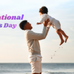 A father joyfully lifting his child in the air on a beach during sunset, with the text "International Father's Day," symbolizing love, trust, happiness, and the special bond between a father and child.