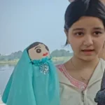 A young student demonstrating handmade cloth puppets as part of an environmental awareness and creative learning project.