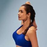 Malaika Arora performing a yoga stretch in a royal blue workout outfit, showcasing flexibility, fitness, and a healthy lifestyle.
