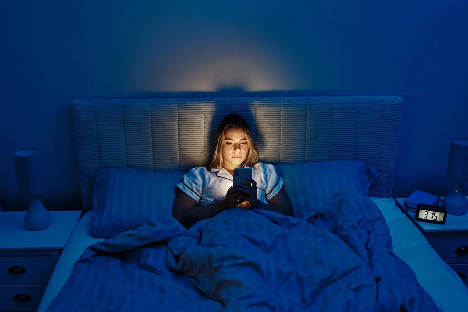 Woman using a smartphone in bed at night, highlighting the impact of screen light on sleep