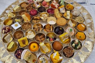 A beautifully arranged traditional Indian sweet platter featuring assorted mithai, dry fruits, and festive delicacies in small golden bowls.