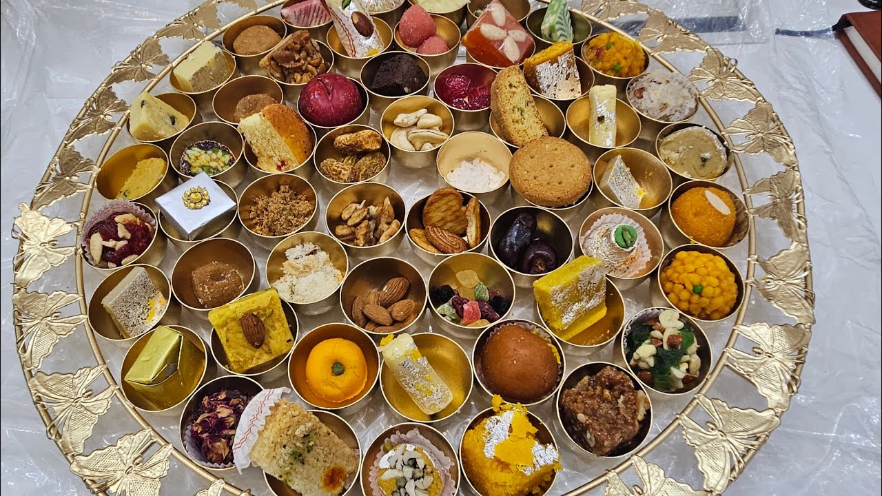 A beautifully arranged traditional Indian sweet platter featuring assorted mithai, dry fruits, and festive delicacies in small golden bowls.