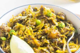 Traditional Bengali cabbage and green peas curry served in a bowl with lemon wedge.